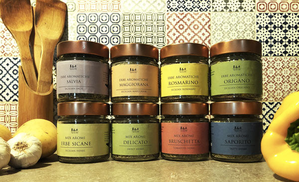 8 aromi in barattolo di vetro con etichette colorate e tappi color rame con sfondo piastrelle cucina attrezzi in legno