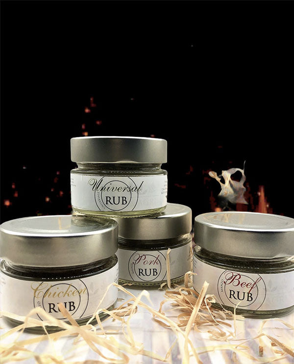 4 rubs per carni verdure e pesce in in barattolo di vetro con etichetta bianca e tappo argento in studio con sfondo nero e fiamme