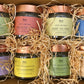 8 aromi in barattolo di vetro con etichette colorate e tappi color rame in scatola di cartone aperta avvolti dalla paglia